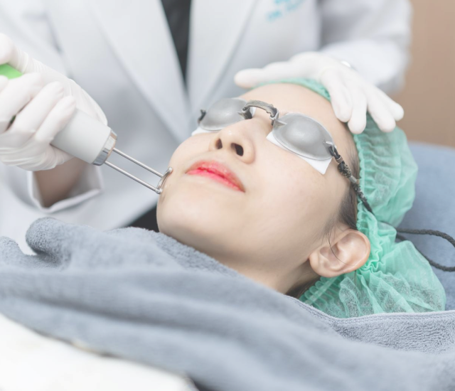 Doctor treating a patient's face with a laser handpiece during the Pigmentation Programme